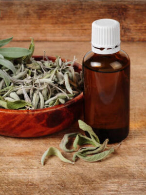 Glass bottle with sage oil, dried and fresh sage over wooden background